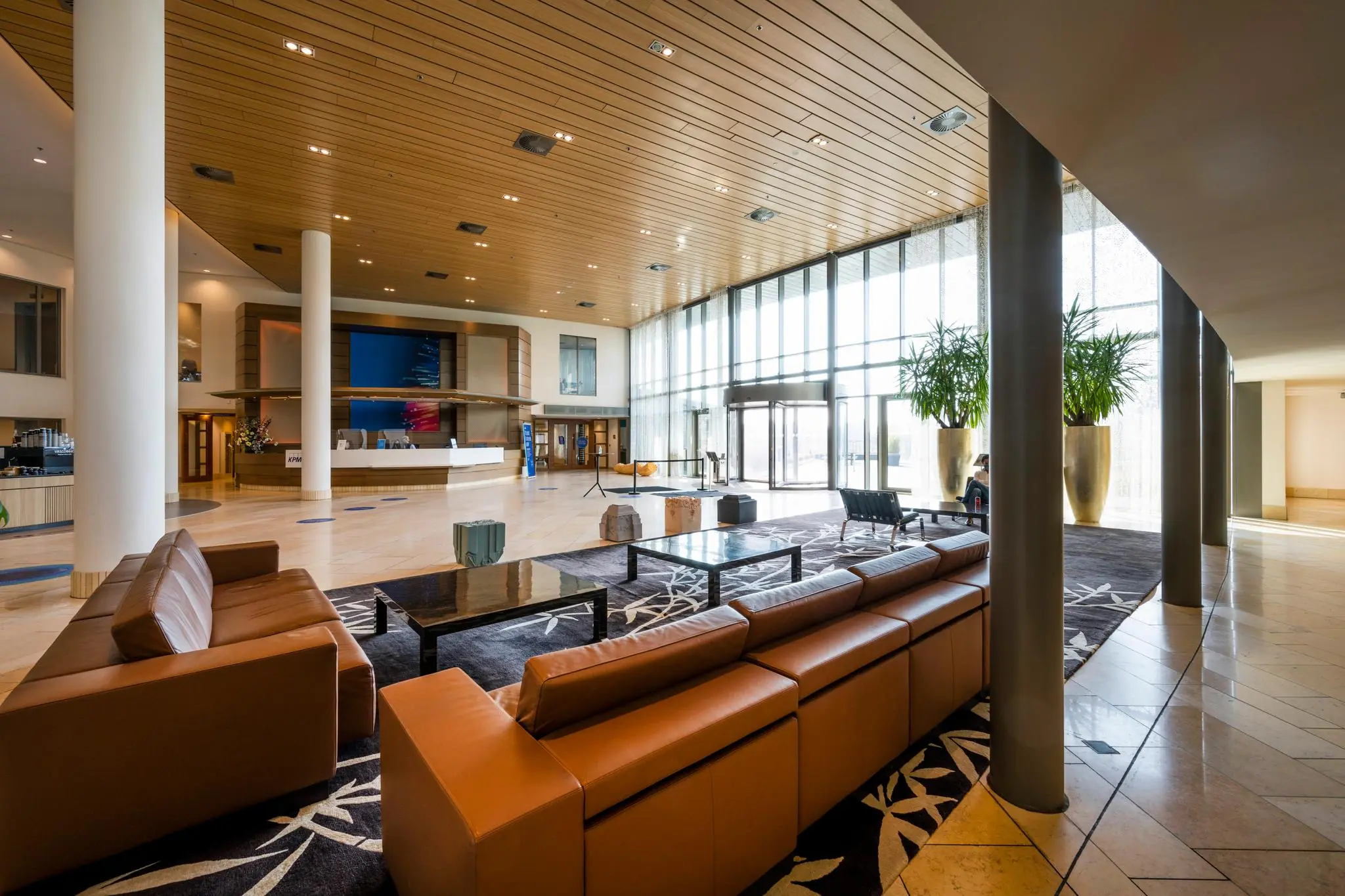 Moderne en ruime ontvangsthal van het kantoorpand aan de Laan van Langerhuize, met zithoeken, receptiebalie en grote raampartijen.